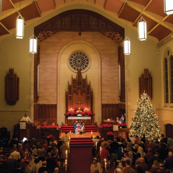 interior of a large church with a bright christmas tree and many people